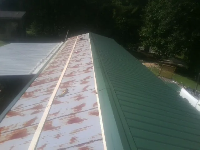 Old rusted panels beside newly installed green metal roofing — Wind Damage Roof Repair by Roofing Brothers in Whitefish