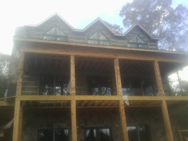 Dormers and porch framing on a large log home under construction — Roof Coating work by our crew in Whitefish