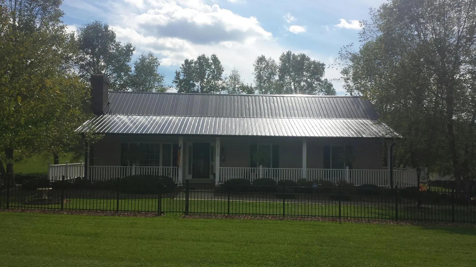 Gray metal roof on a brick ranch with a full width front porch — Gutter Guard Installation work by our crew in Whitefish