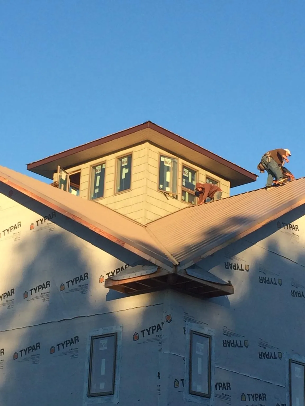 Roofers working around a rooftop cupola on a new metal roof at sunset — Roof Waterproofing in Whitefish by Roofing Brothers